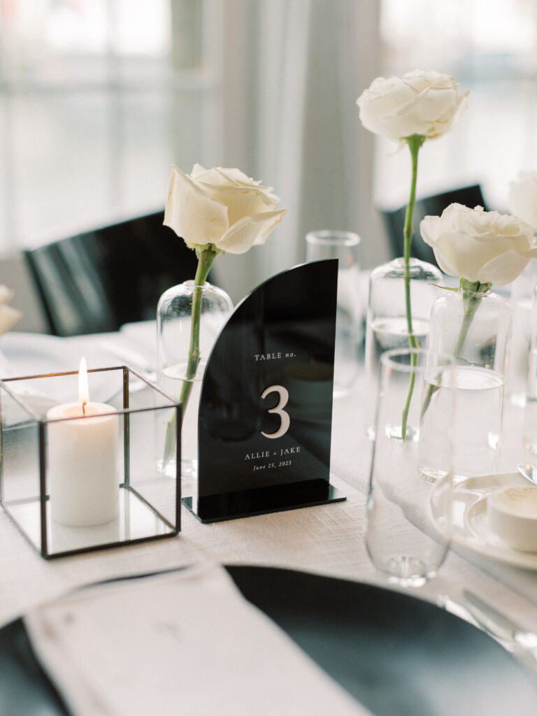 Black acrylic table number sign with white typography on reception table