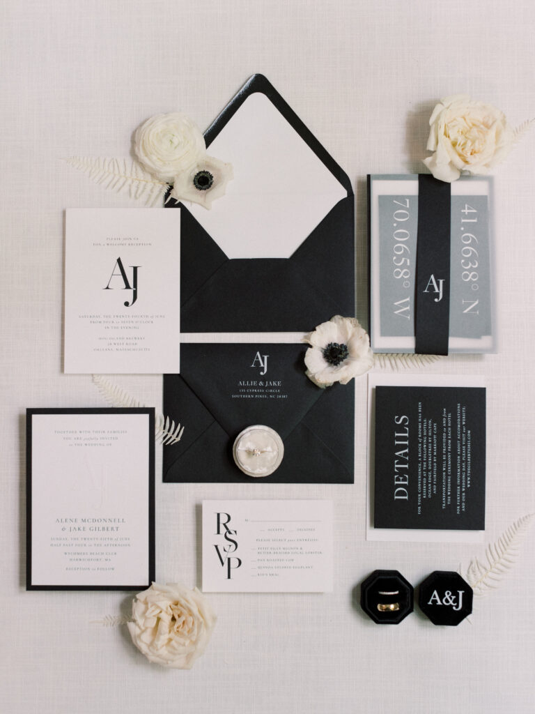 Flat lay of custom black and white wedding invitations with monogram and RSVP card