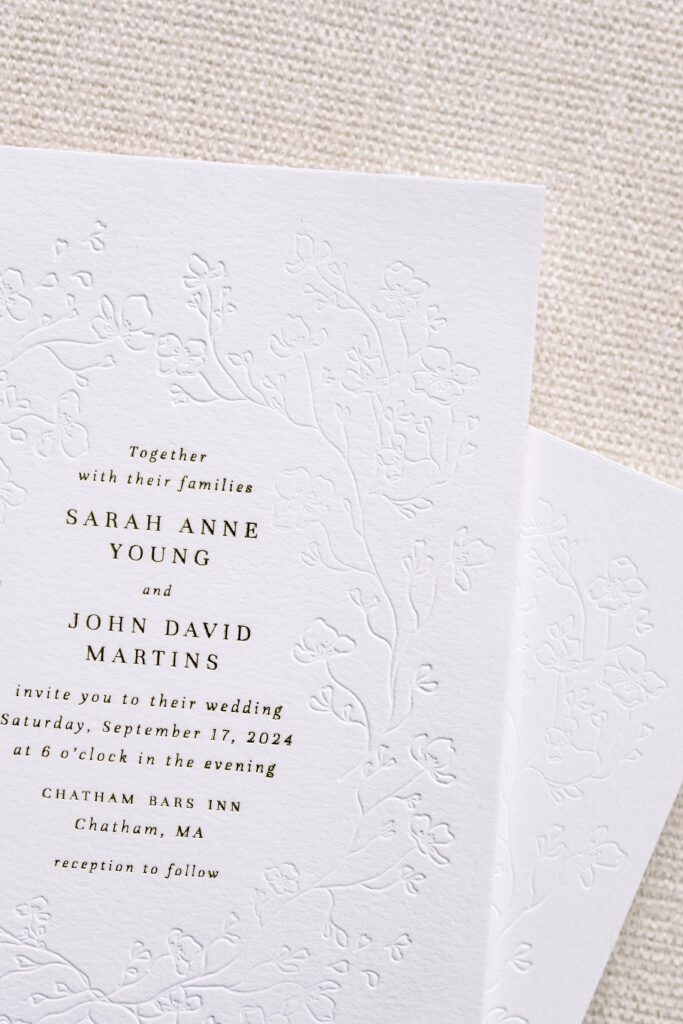A minimalist wedding invitation featuring a subtle blind embossed floral border on soft white cotton paper. Printed with classic black letterpress, this design blends texture and typography for a refined and romantic wedding suite—ideal for coastal or garden-inspired celebrations.