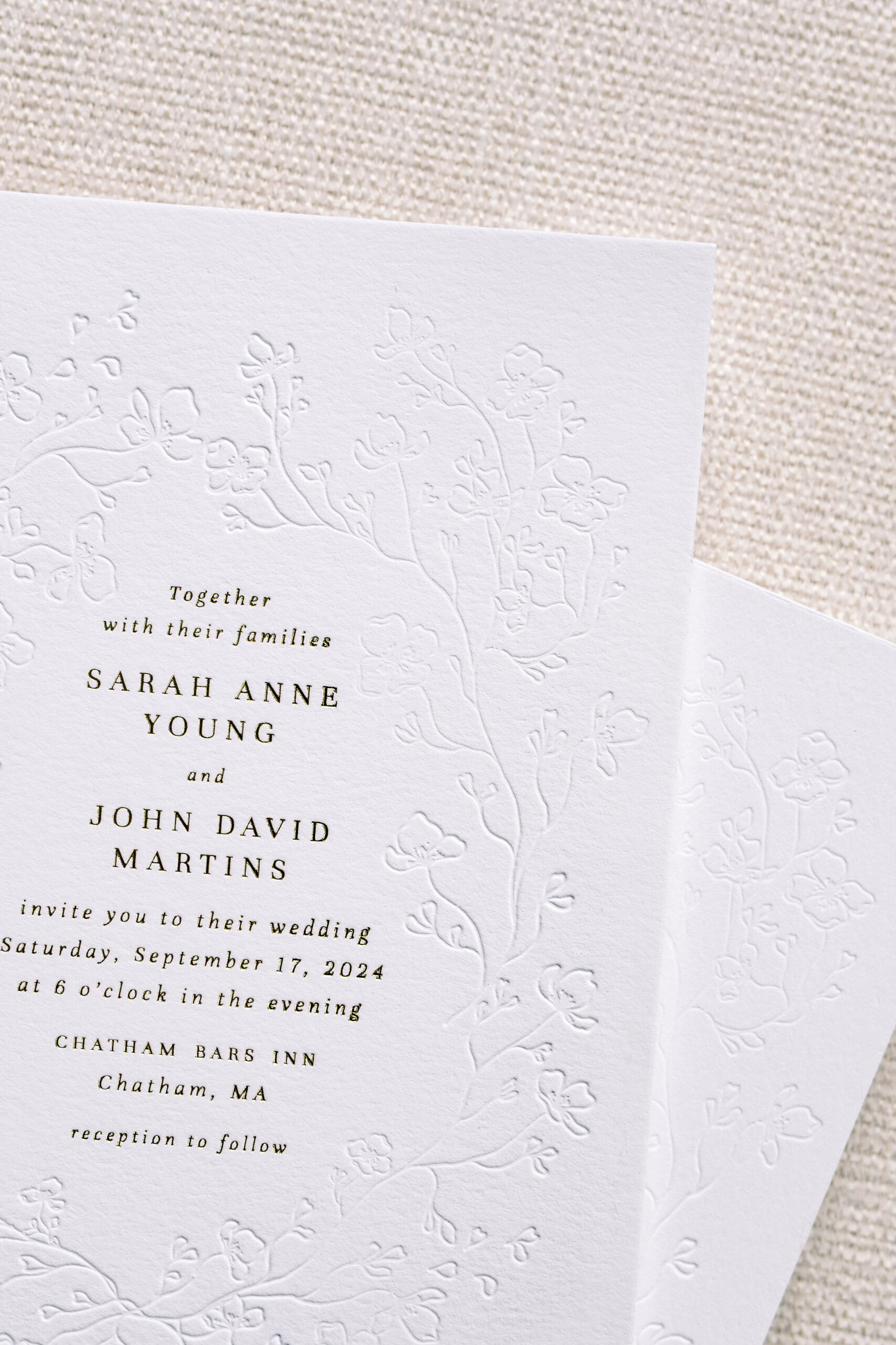 A minimalist wedding invitation featuring a subtle blind embossed floral border on soft white cotton paper. Printed with classic black letterpress, this design blends texture and typography for a refined and romantic wedding suite—ideal for coastal or garden-inspired celebrations.