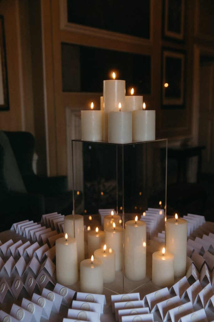 White candle display with tented escort cards with white wax seals and table numbers for an elegant wedding