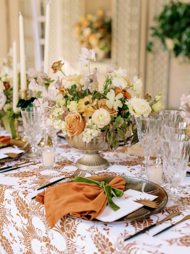 Elegant wedding table setting with a rust napkin, green velvet ribbon, and floral centerpiece