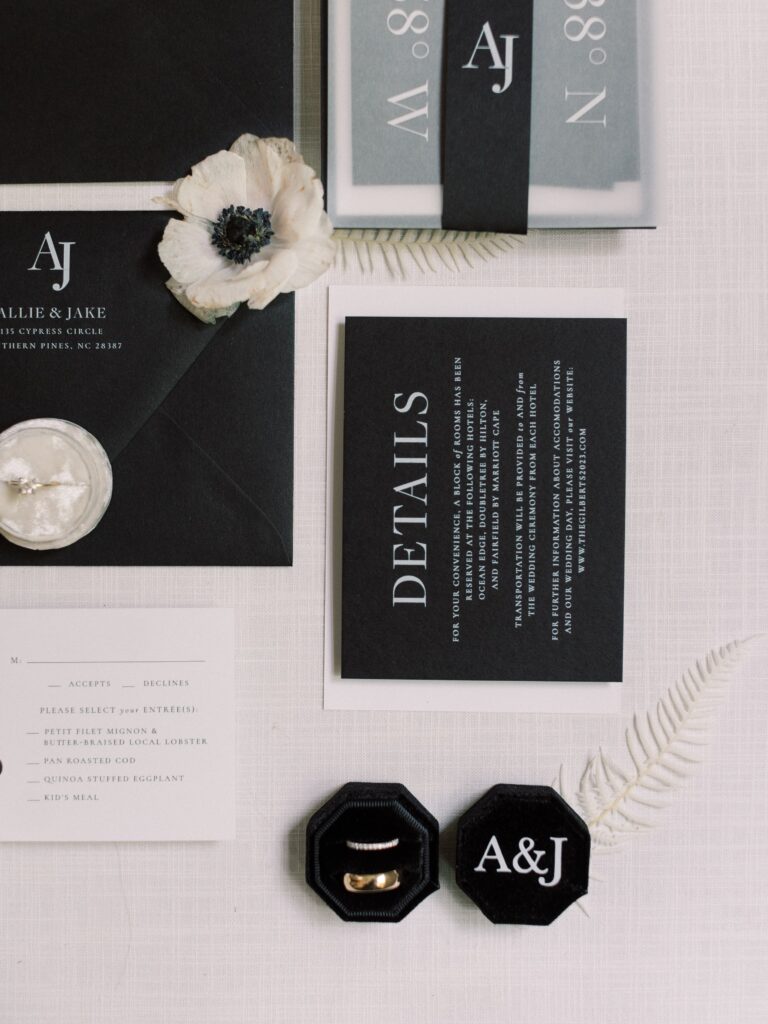 A bold and modern black and white wedding invitation suite featuring a custom monogram, vellum belly band, and classic serif fonts. Paired with minimalist RSVP and details cards, this suite is perfect for a formal or editorial-style wedding. Styled with white florals and black velvet ring boxes for a dramatic finish.